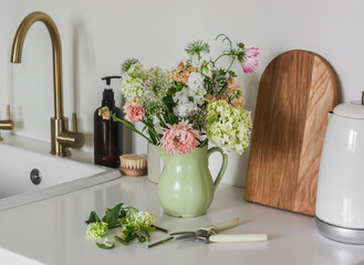Morning routine - a bouquet of summer garden flowers in a ceramic jug, pruner, electric kettle,...