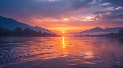 Naklejka premium Sunset over a River with Mountain Silhouette