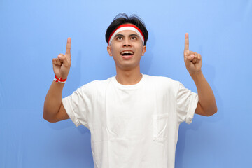 Indonesian man in white shirt and Indonesian flag posing pointing finger to the empty space with...