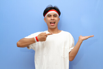 Indonesian man in white shirt and Indonesian flag posing pointing to the his open hand palm with happy excited face,Indonesian independence day concept