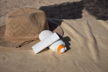 Jars with creams on the background of a towel and a hat. Skin care products for a summer vacation. Women's skin care on a trip.