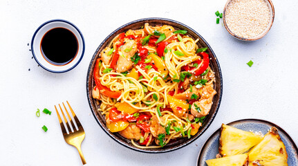 Egg noodles with stir fried chicken, pineapple, paprika, green onion, ginger, garlic, soy sauce and sesame seeds. White background, top view