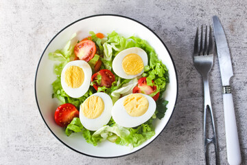 salad and boiled egg in a plate with fork and knife