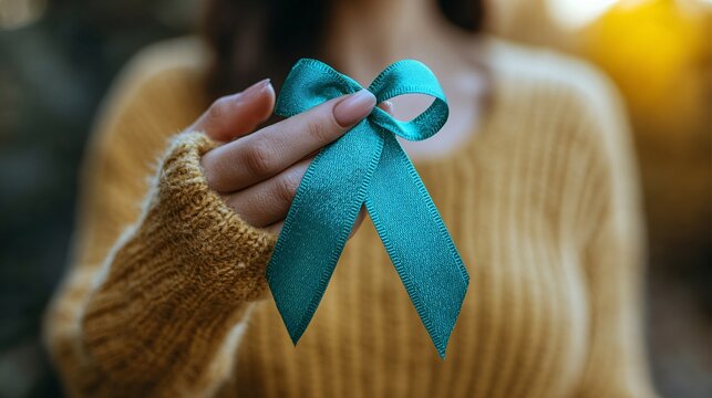 Close-up of a woman's hand with a teal ribbon, highlighting ovarian cancer and PCOS awareness for health advocacy.