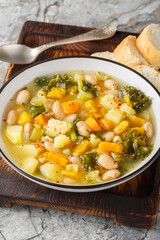 Zuppa Frantoiana italian bean soup with pumpkin and vegetables closeup on the bowl on the wooden board. Vertical