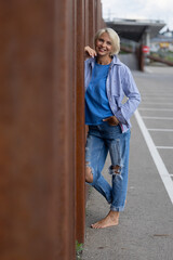 Beautiful and attractive blonde woman in stylish ripped jeans, relaxed in an industrial urban setting