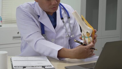 A male doctor in leather works at the table in the bone disease clinic, addressing issues such as cervical spine disease, osteoporosis, herniated discs, and more with expert care.
