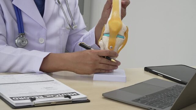 A male doctor in leather works at the table in the bone disease clinic, addressing issues such as cervical spine disease, osteoporosis, herniated discs, and more with expert care.