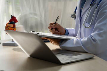 A male doctor sits at a desk in the heart clinic, consulting online and giving advice. The vascular surgery clinic offers an electrocardiogram service with modern technology and expert care.