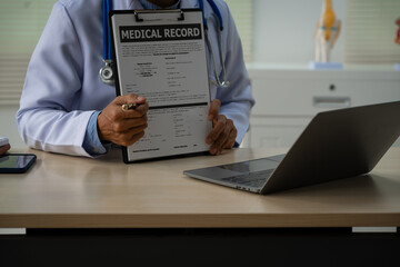 A male doctor sits at a desk in the heart clinic, consulting online and giving advice. The vascular surgery clinic offers an electrocardiogram service with modern technology and expert care.