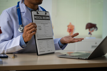 A male doctor sits at a desk in the heart clinic, consulting online and giving advice. The vascular surgery clinic offers an electrocardiogram service with modern technology and expert care.