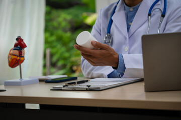 A male doctor sits at a desk in the heart clinic, consulting online and giving advice. The vascular surgery clinic offers an electrocardiogram service with modern technology and expert care.