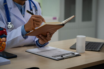 A male doctor sits at a desk in the heart clinic, consulting online and giving advice. The vascular surgery clinic offers an electrocardiogram service with modern technology and expert care.