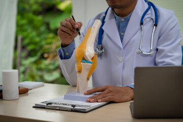 A male doctor in leather works at the table in the bone disease clinic, addressing issues such as cervical spine disease, osteoporosis, herniated discs, and more with expert care.