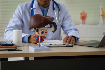 A male doctor sits at a table in a liver disease clinic, giving online advice on hepatitis A, D, E,...