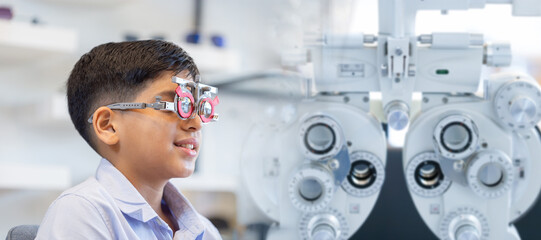 Boy doing eye test checking examination with optometrist in optics store, Indian kid boy choosing eyeglasses in optics store
