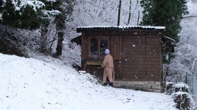 Curious caucasian woman explore an abandoned wooden cottage, carefully watching inside through the window. Nosy neighbour stalking or snooping secrets, gossip and rumour. Stalker peeping people.