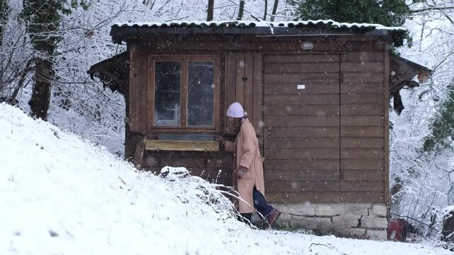 Curious caucasian woman explore an abandoned wooden cottage, carefully watching inside through the window. Nosy neighbour stalking or snooping secrets, gossip and rumour. Stalker peeping people.