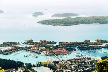 Fototapeta premium A stunning aerial view of a tropical island resort in the Seychelles, featuring a pristine marina filled with yachts and surrounded by lush vegetation