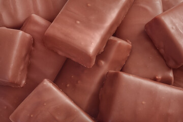 The chocolate bars in chaotic heap. The sweet energetic cocoa dessert with a lot of calories. Closeup view.