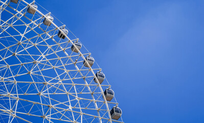 white Ferris wheel on background a bright blue sky in the amusement park in summer with copy space