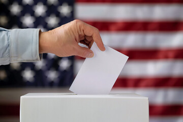 Concept for United States presidential election with ballot paper being put in box by male hand