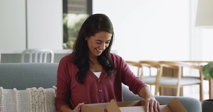 Electronic commerce client get parcel. Woman sit on sofa hold small cardboard box opening received package from friend, feels satisfied with bought goods, good quality and express delivery services
