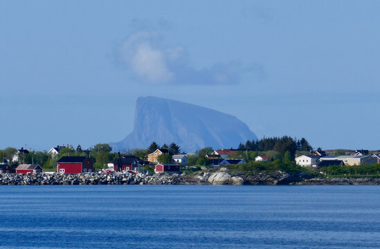 A picturesque Norwegian coastal village set against the dramatic backdrop of the towering Lovund mountain