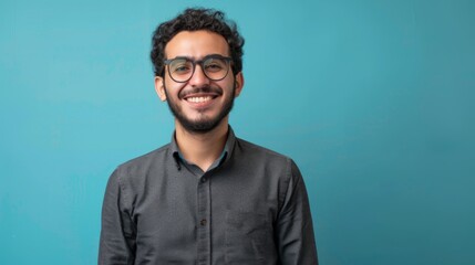 Fototapeta premium Smiling confident arab young man,&nbsp;male student,&nbsp;professional employee or programmer standing isolated on blue background.&nbsp;Happy handsome ethnic guy wearing shirt and glasses