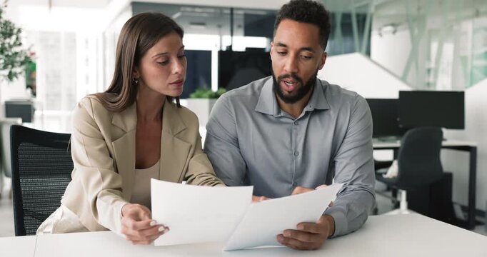 Two multiethnic colleagues reviewing legal papers important documents engaged in collaborative work-related discussion, brainstorm ideas for new project, analyze written data, working on joint task