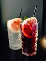 delicious refreshing cocktail with fresh grapefruit and fragrant mint in a beautiful glass cup with a black straw in a cozy nice café