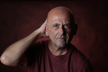 Serious mature man touching his head with hand on red background