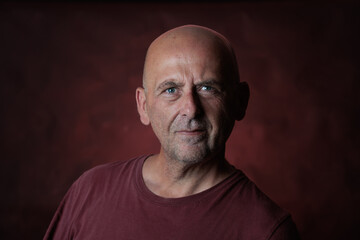Fototapeta premium Mature man with shaved head and goatee posing on red background