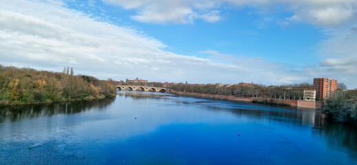 Tranquil Garonne River at Sunrise, Bathed in Golden Light Under a Clear Blue Sky, Toulouse