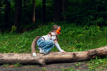 A girl with cat mask, tail and gloves doing Quadrobics in the forest.