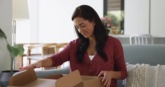 Woman sit on sofa opening received parcel box feels frustrated, dissatisfied because of wrong or damaged items or poor quality, goods not match on-line description. Purchase return, negative feedback