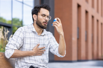Young man using asthma inhaler outdoors for respiratory relief