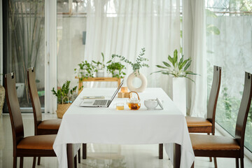 Dining table with laptop and tea in the room