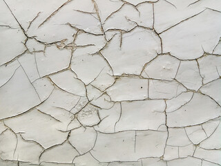 Light gray paint cracks texture on the wall surface. Vintage grunge background.
