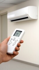 A hand reaches for the remote control to turn on the air conditioner in a bright, clean room, creating a comfortable environment