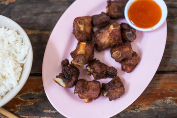 Fried pork ribs on pink dish served with chilli sauce. This menu looks appetizing