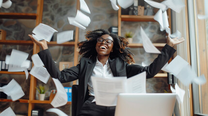 Young happy successful employee, business black woman, working in office, throwing away paper sheets, documents, celebrating freedom from routine work, end of working day. Motion blur, selective focus