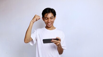 Fototapeta premium Asian young man happy wearing white shirt playing game on mobile phone