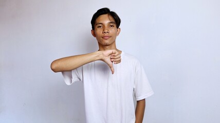 Asian young man wearing white shirt gesturing thumbs down
