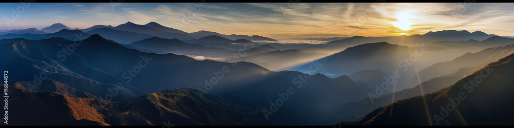 Wall mural the mountains are covered in a blanket of fog and the sun is setting behind them
