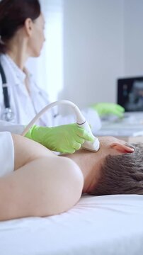 Doctor woman with green medical gloves performing neck ultrasound exam on male patient. Thyroid gland examination. Medicine concept