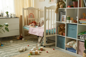 Cozy baby nursery featuring a crib with stuffed animals, organized shelves, and various wooden toys...
