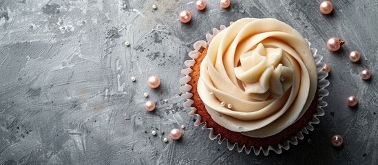 Top view of a birthday cupcake adorned with a pearl decoration and buttercream icing on a gray backdrop, with copy space image.