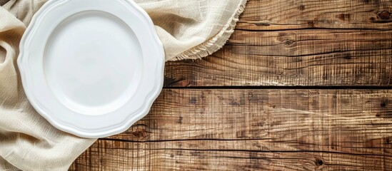 Top view of a white plate with a napkin on a wooden table background with copy space image.