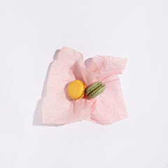 Fruit flavored macarons on pastel pink wrapping paper, French pastries concept.